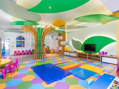 Barevný dětský koutek v hotelu s sedacími pytli, herními podložkami a velkou lezeckou konstrukcí.