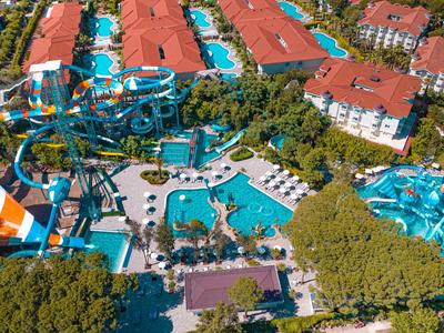 Luftaufnahme eines Hotels mit großem Wasserpark und Wasserrutschen, umgeben von Bäumen.