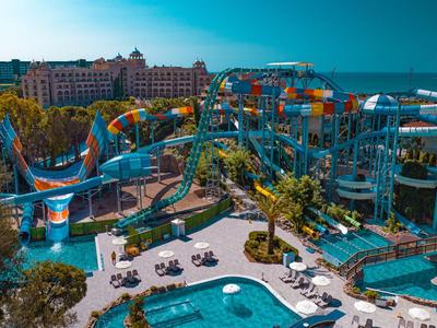 Hotel mit Wasserpark, großen bunten Wasserrutschen und Poollandschaft unter blauem Himmel.