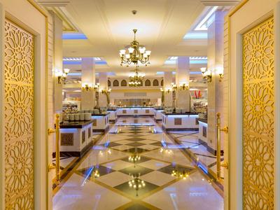 Luxuriöser Hotel-Essbereich mit goldverzierten Türen und glänzendem Marmorfußboden.