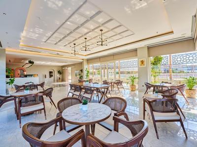 Innenraum eines hellen Hotelrestaurants mit Marmor-Tischen und braunen Stühlen.