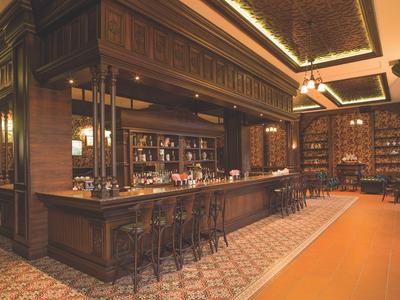 Elegante Hotellounge mit hölzernem Tresen und Regalen voller Flaschen.