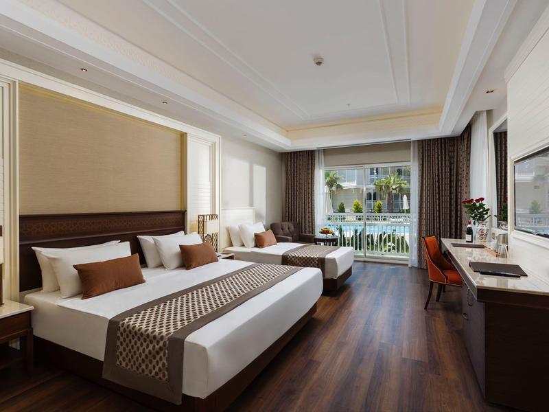 Modern hotel room with a large bed, wooden floor, desk, and balcony view.