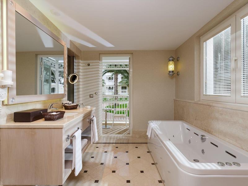 Spacious bathroom with large bathtub, double sinks, and a door leading to an outdoor area.
