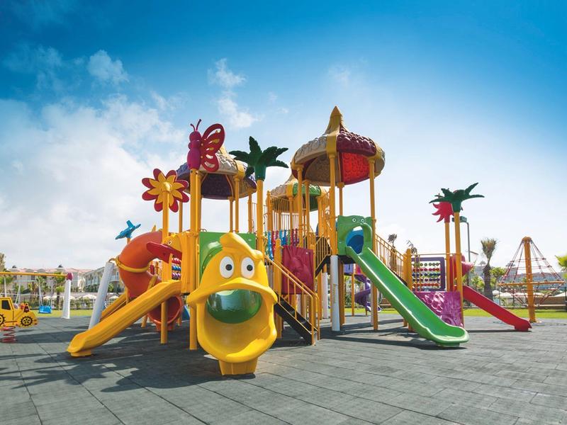 Colorful outdoor playground with slides and climbing structures under a blue sky.