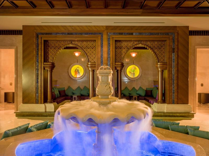 Luxurious hotel lobby with elegant fountain and cozy seating areas in warm lighting.