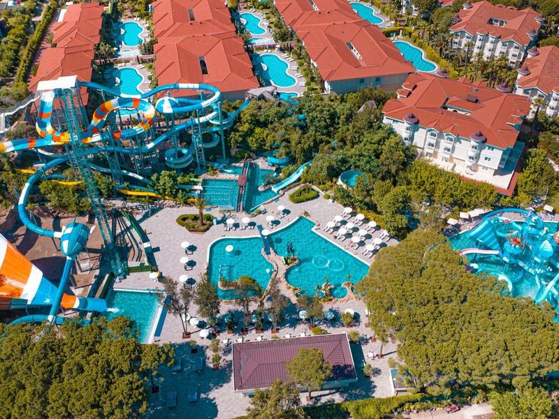 Water park with slides and pools surrounded by hotel buildings and lush greenery.