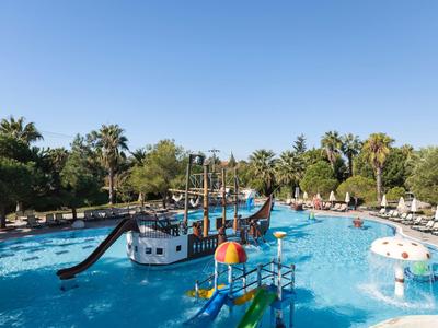 Parco acquatico con area giochi a forma di nave pirata e scivoli in piscina di un hotel sotto un cielo limpido