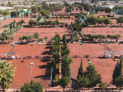 Přehled červených střech hotelového komplexu s stromy a parkovacími místy mezi nimi.