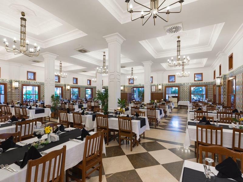Ampia sala da pranzo con tavoli apparecchiati e illuminazione moderna in un hotel.