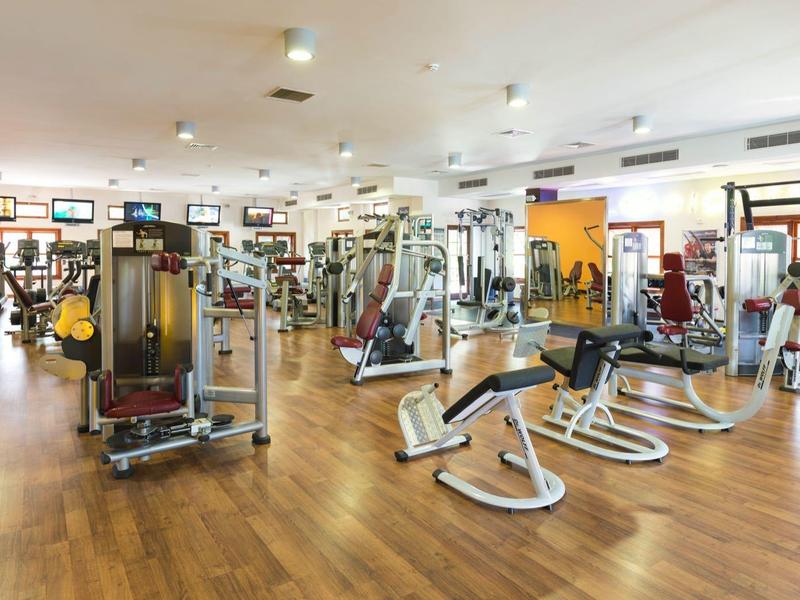 Una palestra luminosa e spaziosa con attrezzature moderne su pavimento in legno.