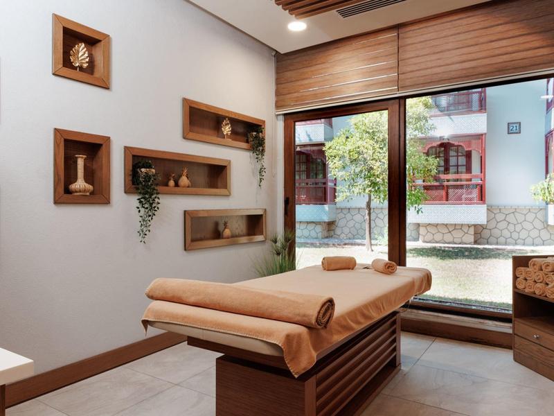 Sala massaggi luminosa con mobili in legno, decorazioni alle pareti e vista su un cortile interno.