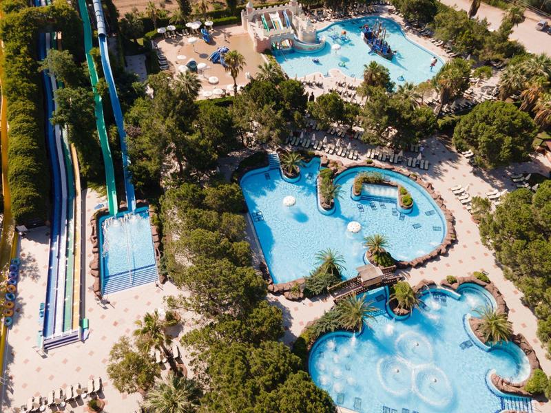 Vista aerea di un parco acquatico con scivoli, piscine e aree verdi circostanti.