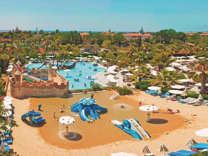 Grande parco acquatico con piscine, scivoli d'acqua e ombrelloni in un resort alberghiero.