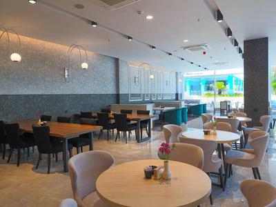 Nowoczesna jadalnia śniadaniowa z stołami, krzesłami i dostępem do zewnętrznego obszaru w hotelu.