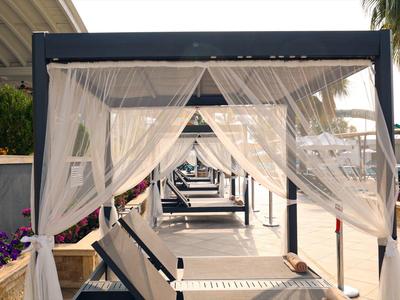 Luksusowe leżaki na zewnątrz otoczone białymi zasłonami na hotelowym tarasie.