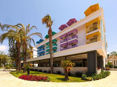 Nowoczesny budynek hotelowy z kolorowymi balkonami i palmami na pierwszym planie pod czystym niebem.