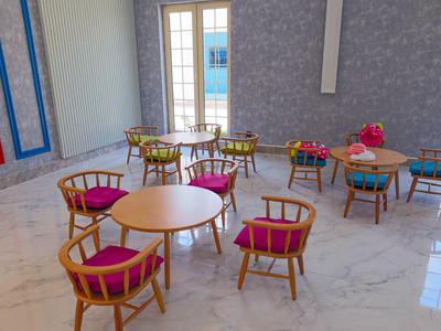 Nowoczesna jadalnia z okrągłymi drewnianymi stołami i krzesłami z różowymi poduszkami.