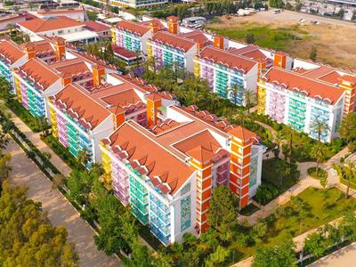 Kolorowy kompleks hotelowy z czerwonymi dachami i wieloma budynkami otoczonymi zielenią.