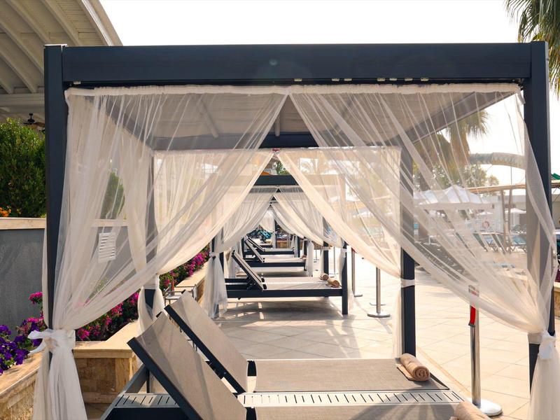 Luksusowe leżaki na zewnątrz otoczone białymi zasłonami na hotelowym tarasie.