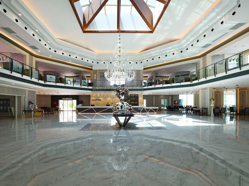 Przestronne, eleganckie lobby hotelowe z marmurową podłogą i żyrandolem pod szklanym dachem.