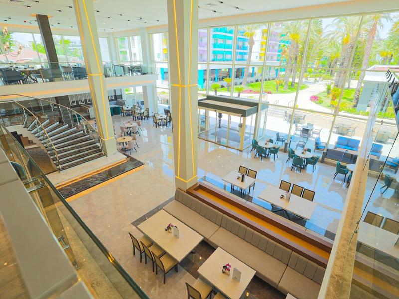 Nowoczesna część restauracyjna hotelu z miejscami do siedzenia wewnątrz i na zewnątrz z widokiem na basen i ogród.