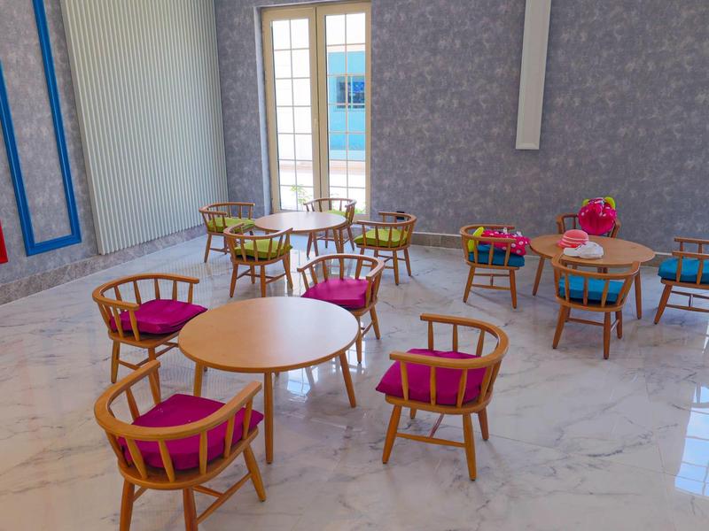 Nowoczesna jadalnia z okrągłymi drewnianymi stołami i krzesłami z różowymi poduszkami.