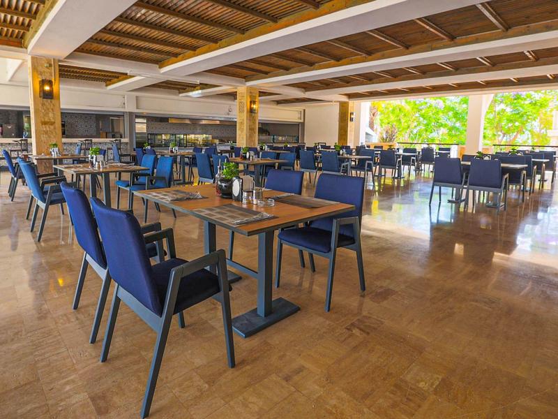 Przestronna część restauracyjna z niebieskimi krzesłami i drewnianymi stołami w otwartej przestrzeni