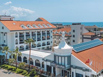 Edificio dell'hotel con facciata bianca, tetti rossi e vista sul mare sullo sfondo.