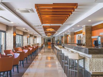 Sala colazione moderna con sedie marroni, bancone bar e pavimento in marmo chiaro