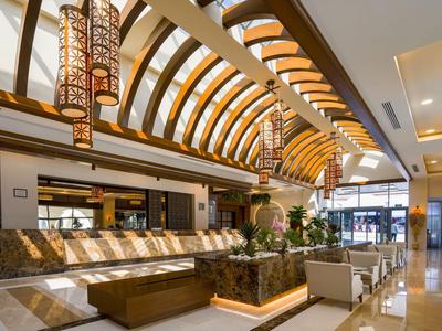 Jasna lobby hotelowa z łukowatymi drewnianymi sufitami i nowoczesnym miejscem do siedzenia.