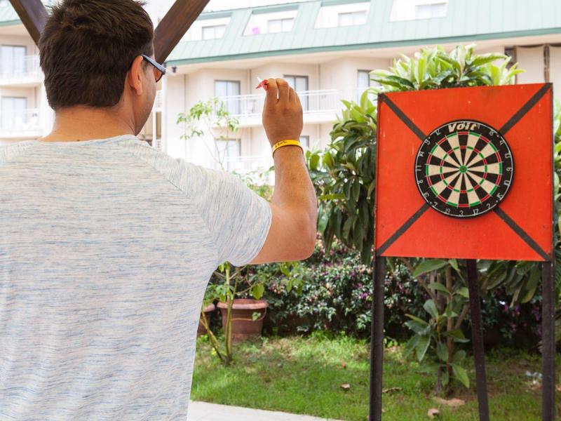 Uomo che lancia una freccetta su un bersaglio nel giardino di un hotel