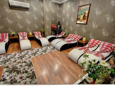 Sala relax con divani curvi, cuscini rossi, tappeto floreale e decorazioni murali.