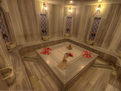 Sala hammam con panchine in pietra e fiori sul tavolo centrale.