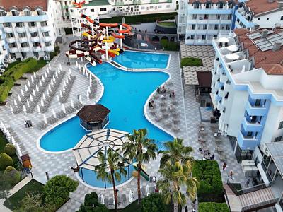 Vista di una piscina dell'hotel con scivoli d'acqua, ombrelloni e edifici su più piani.