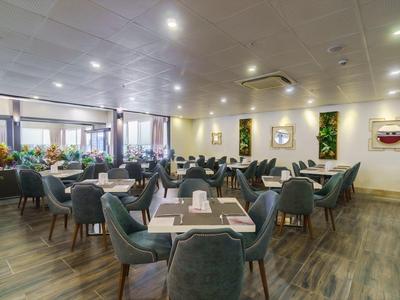 Sala da pranzo moderna e ben illuminata con tavoli eleganti e sedie confortevoli.