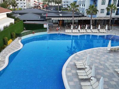 Grande piscine extérieure avec chaises longues et parasols dans un jardin d'hôtel