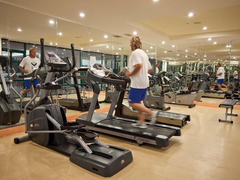 Palestra con molte macchine e una persona che corre sul tapis roulant.