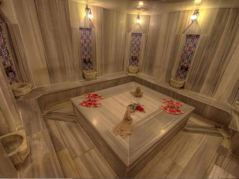Sala hammam con panchine in pietra e fiori sul tavolo centrale.