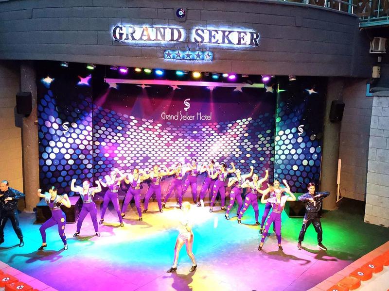 Spettacolo sul palcoscenico con ballerini e luci colorate in un teatro dell'hotel.