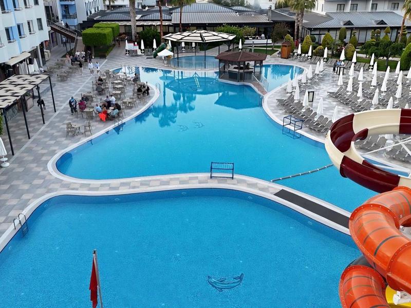 Piscina moderna dell'hotel con design curvo, sdraio e scivolo d'acqua