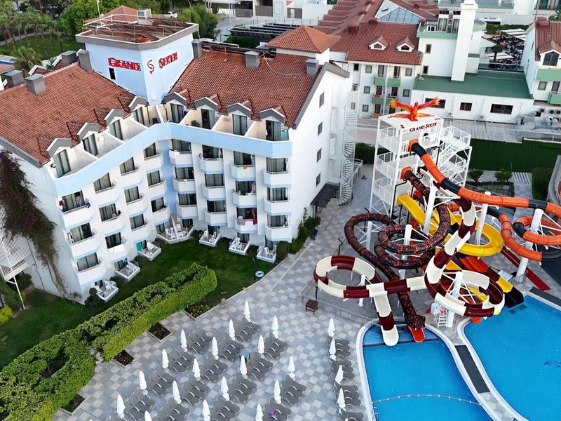 Complesso alberghiero con una grande piscina, scivoli d'acqua e edificio bianco con tetti rossi