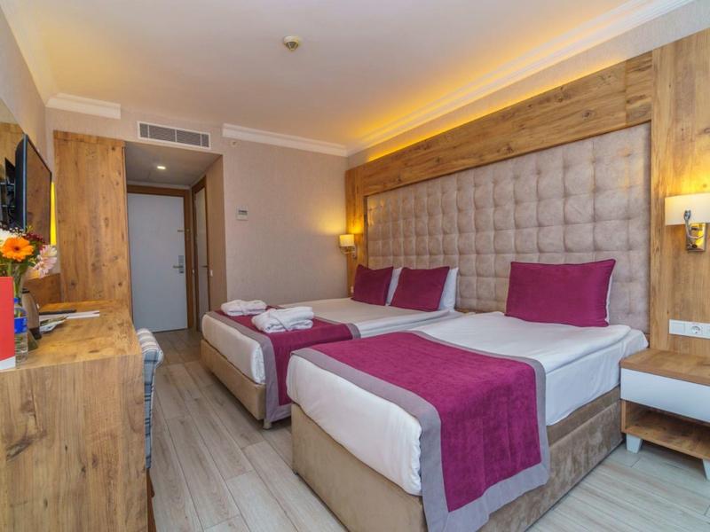 Camera d'hotel moderna con due letti singoli, accenti in legno e tessuti viola