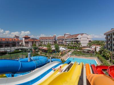 Wasserrutschen und Pools in einer Hotelanlage bei strahlendem blauem Himmel.