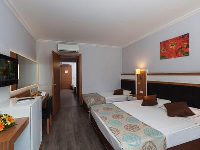 Modernes Hotelzimmer mit zwei Einzelbetten, Holzmöbeln und heller Wanddekoration.