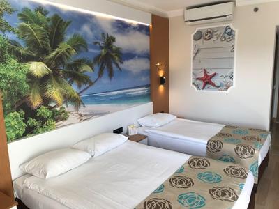 Zimmer mit drei Betten, tropische Wandmalerei, Klimaanlage und maritimer Dekoration.