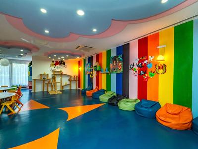 Bunter Spielraum mit Sitzsäcken, Holzspielzeug und Regenbogenwand für Kinder.