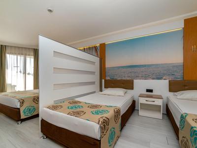 Modernes Hotelzimmer mit drei Einzelbetten, maritimem Wandbild und hellem Holzboden.