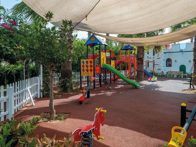 A colorful children's playground with slides and swings under a sunshade.