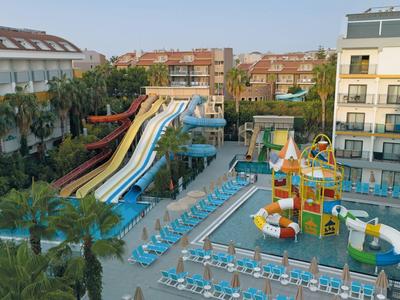 Hotel complex with multiple water slides, a children's pool, and sun loungers outdoors.